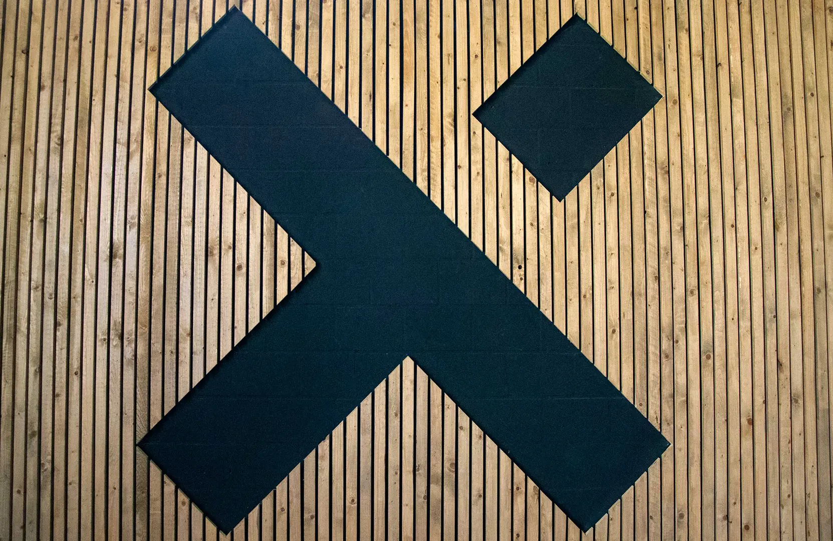 Het logo van U Move verwerkt in een houten muur in de gym