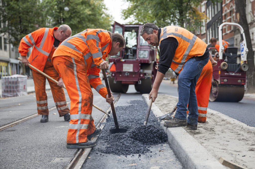 Vier mannen aan het werk met verschillende soorten gereedschap.