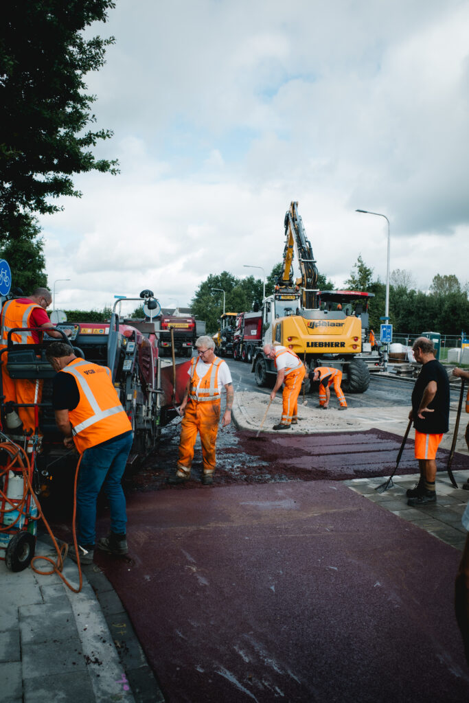 Een drukke werkplek met meerdere medewerkers van VGB Asfalt.